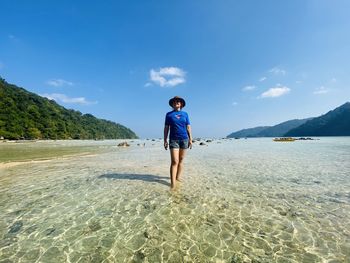 Rear view of man standing on beach against sky