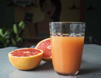 Glass of fresh grapefruit juice on grey table