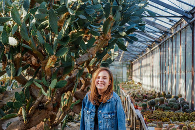 Portrait of smiling young woman standing in greenhouse