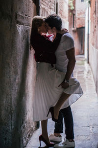 Side view of young couple kissing against wall