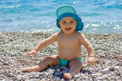 Baby boy at beach near sea. cute baby playing with pebble