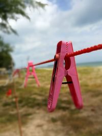 Close-up of clothespins hanging on clothesline against sky