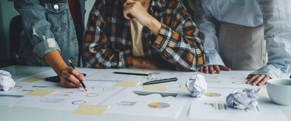 Midsection of business people working on table