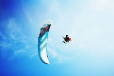 Low angle view of person powered paragliding against sky