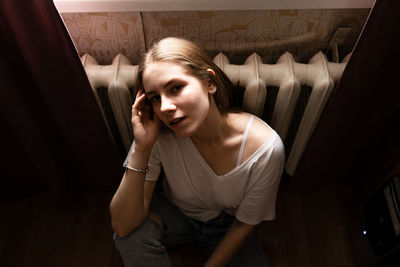 High angle portrait of young woman sitting at home