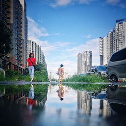 People standing by modern buildings in city against sky