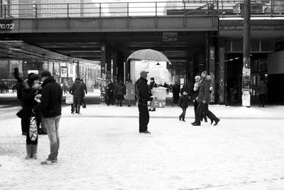 People walking at snowy railroad station