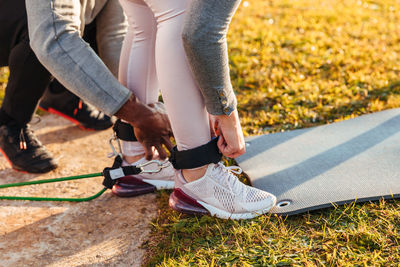 Low section of trainer assisting woman in wearing belts