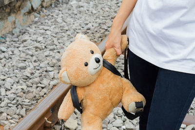 Midsection of woman holding teddy bear while standing on railroad track