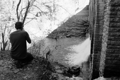 Rear view of man photographing by dam