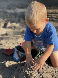 Close-up of boy playing with sand at beach