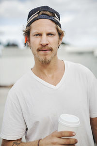 Portrait of confident carpenter holding disposable cup outdoors