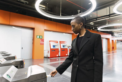 Young woman taking ticket from machine at metro station