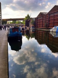 Boats in river against cloudy sky