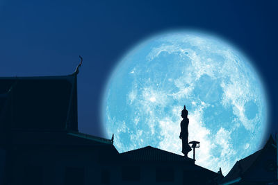 Low angle view of silhouette man standing against building at night