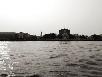 Buildings at waterfront against clear sky