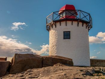 Lighthouse by sea against sky