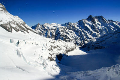 Scenic view of snowcapped mountains against blue sky