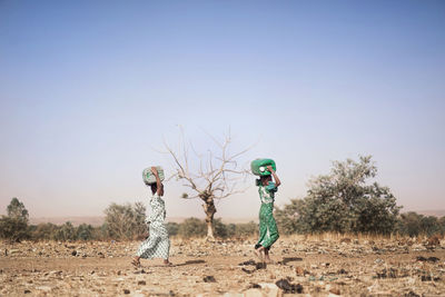 Full length of girls carrying containers while walking on land