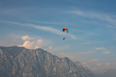 Low angle view of people paragliding against sky