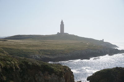 Hercules tower. lighthouse by buildings against clear sky
