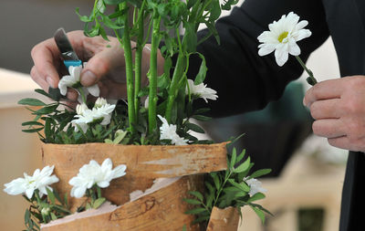 Cropped hands of florist arranging flowers in basket