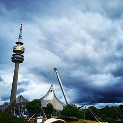 Tower amidst buildings in city against cloudy sky