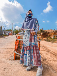 Midsection of woman standing by road against sky