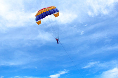 Low angle view of people paragliding against sky