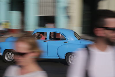 Blurred motion of man driving car on road in city