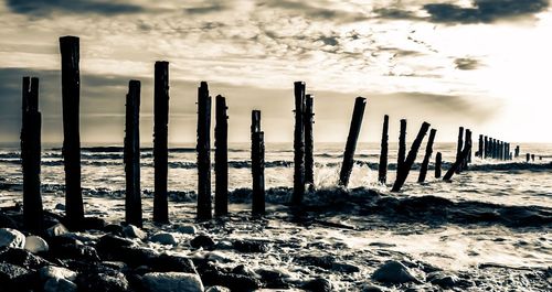 Wooden posts on beach against sky