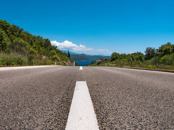 Road by trees against blue sky