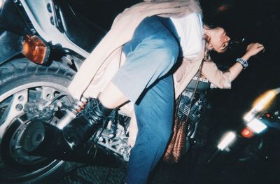 Midsection of man holding umbrella at night