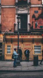 People walking on footpath against building in city