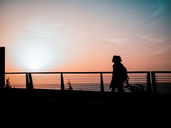 Silhouette man standing on beach against sky during sunset