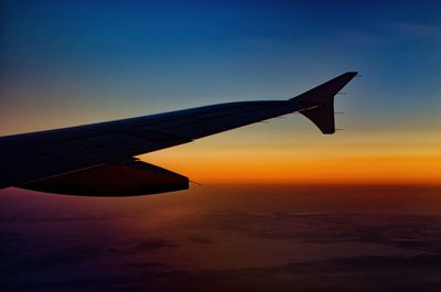 Airplane wing against sky at sunset