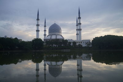 Reflection of mosque in lake against sky