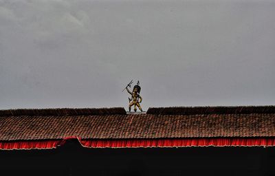 Low angle view of house on roof of building against sky