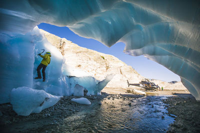 Man ice climbing on glacial ice during adventure helicopter tour