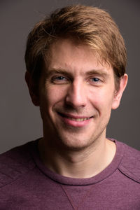 Portrait of smiling young man against black background