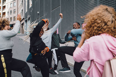 Happy friends dancing on street with woman standing in foreground