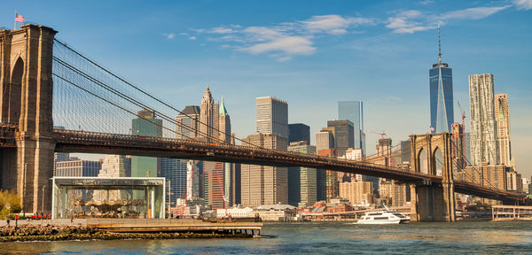 Bridge over river by buildings against sky in city