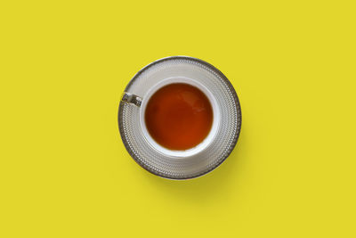 Directly above shot of tea cup against yellow background
