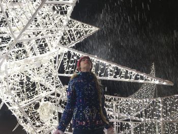 Woman standing against illuminated wall