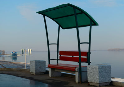 Lifeguard hut on pier at beach against sky