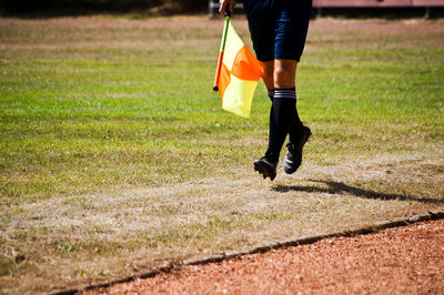 Low section of soccer player with flag running on field