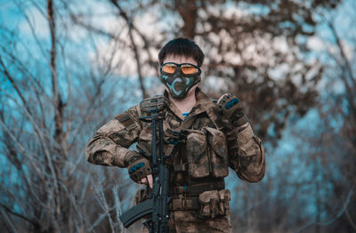 Portrait of young man standing against bare tree