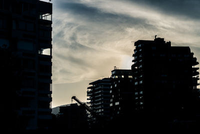 Low angle view of silhouette buildings against sky