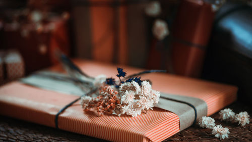 Close-up of flowers with gift on table at home