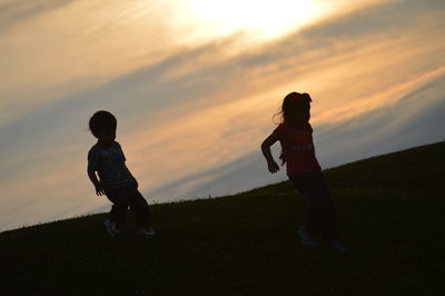 Silhouette of boy jumping on field